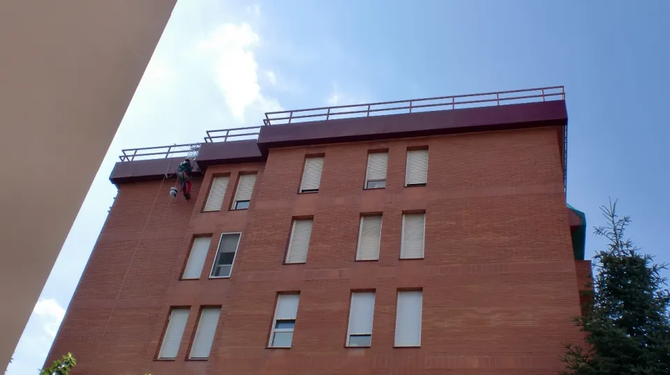 Operario de ServiProject haciendo trabajos verticales en una fachada de ladrillo